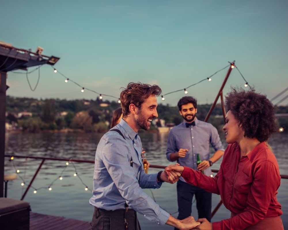 Ein Paar tanzt ausgelassen bei Sonnenuntergang auf dem Schiff – Hochzeitslocation auf dem Wasser